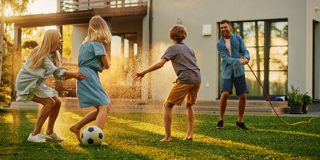 Eine Familie spielt im Garten Fußball.