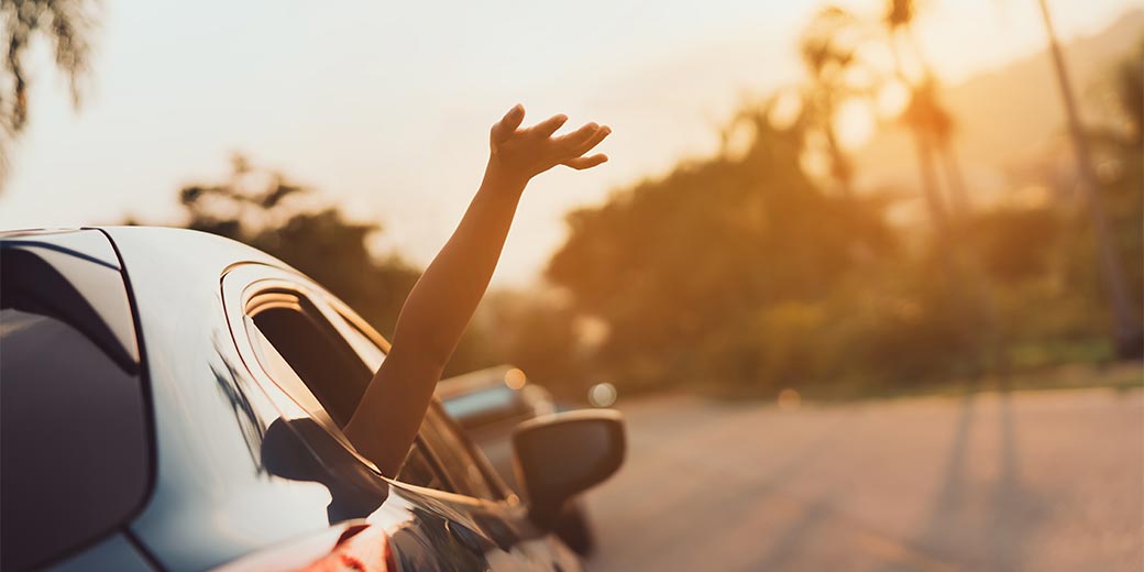 Auto vor Sonnenuntergang mit geöffnetem Fenster und herausragendem Arm