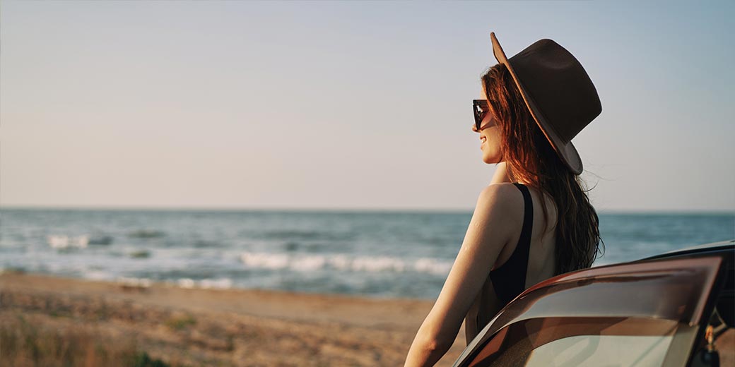 Frau schaut auf das Meer und sitzt im Auto