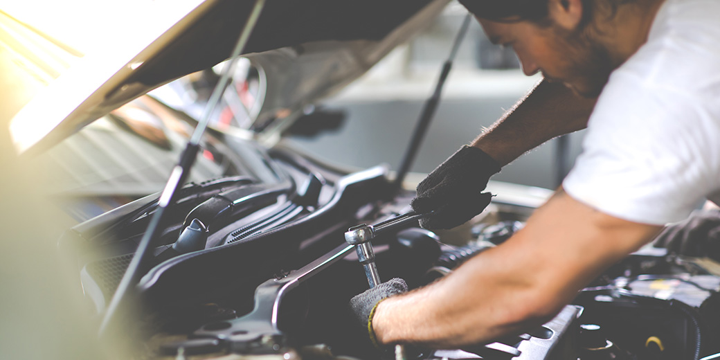 Ein Mechaniker schaut unter die Motorhaube eines Autos.